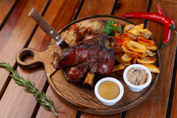 Top view of traditional bavarian knuckle with baked crispy potatoes and classic german braised cabbage on a wooden table