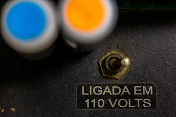 Close up of a vintage old switch with in Portuguese the designation that it has a voltage of 110