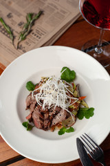 Top view of thai style marbled beef salad with sweet alcoholic strawberry cocktail on a dark wooden table