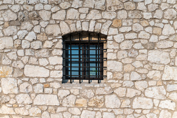 Fototapeta na wymiar Wall made of limestone with a window with a grate.