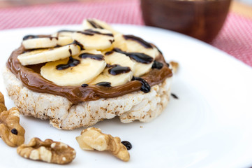 Obraz na płótnie Canvas Rice biscuit with dulce de leche and pieces of banana and nuts. Accompanied with a milk banana smoothie. Added low calorie chocolate.