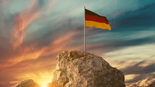 Wehende deutsche Fahne auf Bergspitze im wunderschönen Sonnenuntergang	