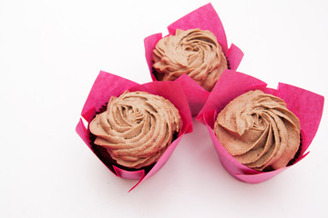 Three cupcakes with cream in pink paper