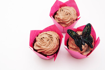 Cupcakes with cream are decorated with sequined butterflies