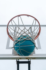 A basketball goes through the net, on a neighborhood playground