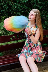 Happy joyful beautiful young woman with candy floss, spun sugar, cotton candy in the park at...