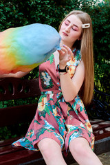 Happy joyful beautiful young woman with candy floss, spun sugar, cotton candy in the park at...