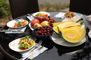 Delicious food from garden served on the table in backyard or terrace. Summer picnic concept. Salad served on the plates.
