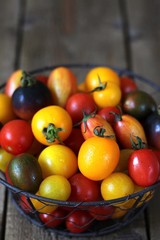 cherry tomatoes are different varieties in the basket, small tomatoes of different colors and types.