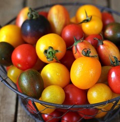 cherry tomatoes are different varieties in the basket, small tomatoes of different colors and types.