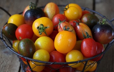 cherry tomatoes are different varieties in the basket, small tomatoes of different colors and types.