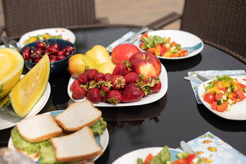 View from side of sweet fruits standing in plate. Delicious strawberry, red cherries and healthy vegetable salad served on table in summer. Concept of vitamins and organic food.