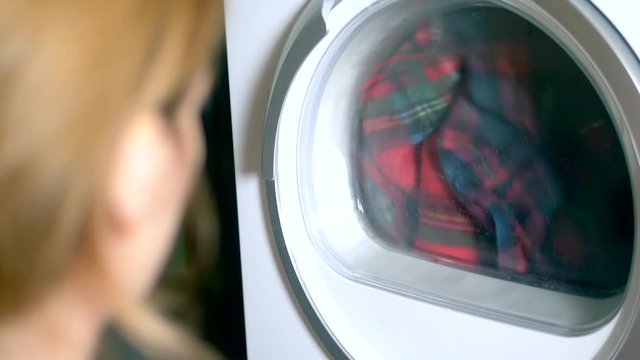 the laundry is dried in a clothes dryer. close-up. woman watching the process of drying clothes in the dryer