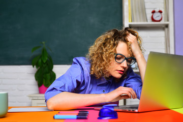 Tired teacher working with laptop in classroom. Hard work. School job. Homework. Education concept. World teachers day. Back to school.