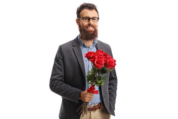 Bearded young man in a holding a bunch of red roses and smiling