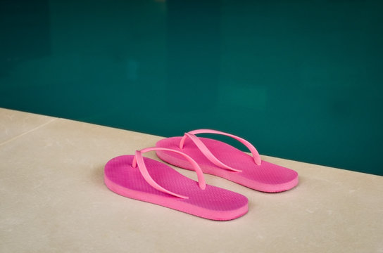 Close-up of pink flip flops at the edge of an indoor pool .