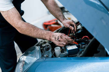 cropped view auto mechanic with mud on hands fixing automobile in car repair station
