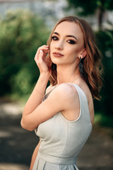 Fototapeta premium Gorgeous young model woman with perfect hair looking at camera posing in the city wearing evening dress.