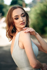 Gorgeous young model woman with perfect  hair looking at camera posing in the city wearing  evening dress.