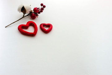 Two hearts a sprig of cotton, a pine cone, red berries, on a white background.