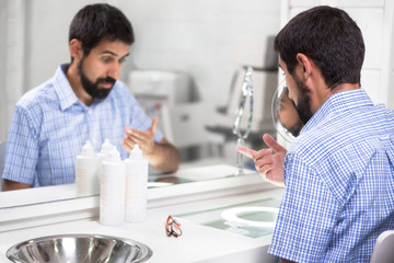 Man putting on contact lens in ophthalmology clinic . 