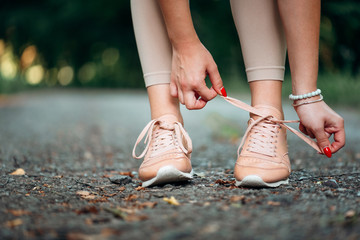 Running shoes - closeup of woman tying shoe laces. Female sport fitness runner getting ready for jogging outdoors on forest path in spring or summer.