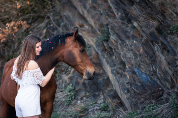 Frau kuschelt mit ihrem Pferd auf einem Felsen