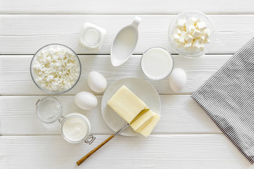 Dairy products from farm with milk, eggs, cottage, butter, yougurt on white wooden background top view