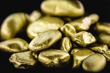 Fototapeta na wymiar Gold nugget, large gold stone closeup isolated on black background. Concept of finance, luxury or wealth.