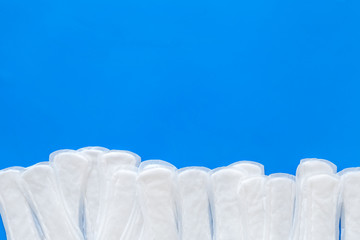 Woman hygiene and menstrual period concept with sanitary pads on blue background top view copyspace