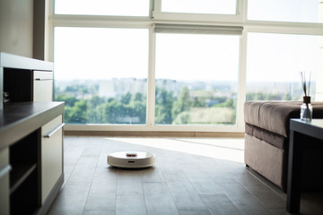 Smart House. Vacuum cleaner robot runs on wood floor in a living room