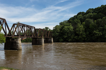 Following a calm river as it passes under a steel train bridge in a small midwestern town