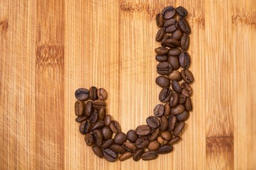 Alphabet letter J made from roasted coffee beans, 3D rendering on wooden table background