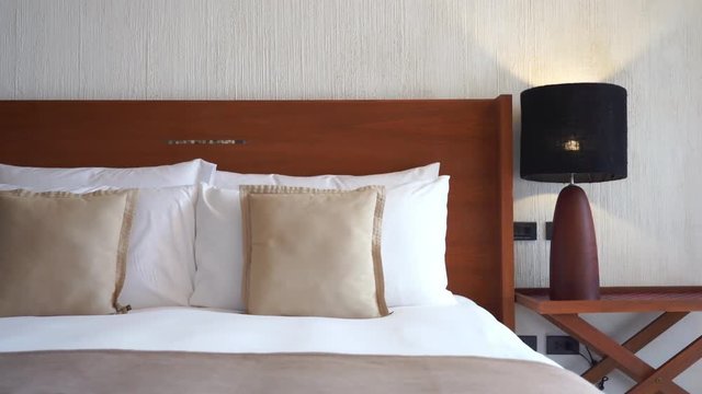 Tilt down from wall to a well-appointed bed bedside table with lamp in a resort hotel.