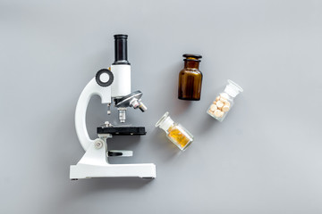 Medical research with microscope, pills in test tube on gray background top view