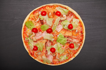 Tasty pizza with various flavored ingredients on a dark background