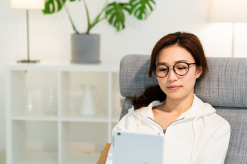 部屋でタブレットを見る女性