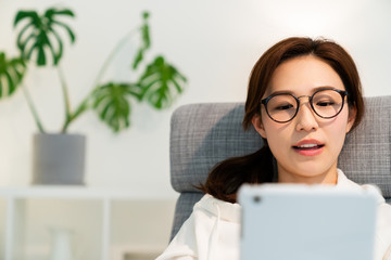 部屋でタブレットを見る女性