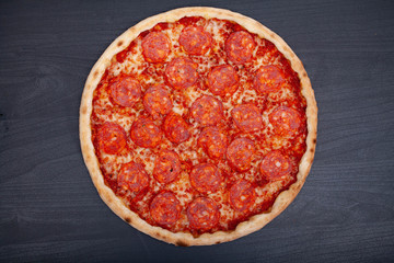 Tasty pizza with various flavored ingredients on a dark background
