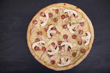 Tasty pizza with various flavored ingredients on a dark background