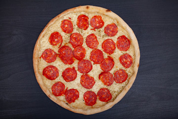 Tasty pizza with various flavored ingredients on a dark background