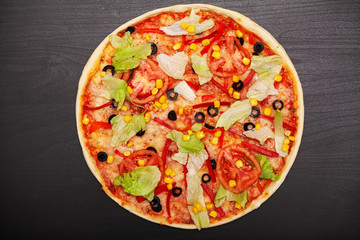 Tasty pizza with various flavored ingredients on a dark background