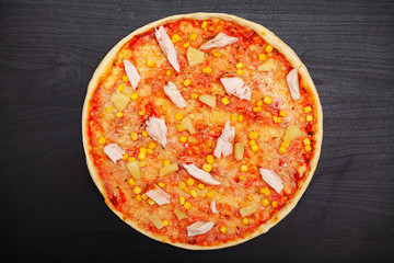 Tasty pizza with various flavored ingredients on a dark background