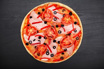 Tasty pizza with various flavored ingredients on a dark background
