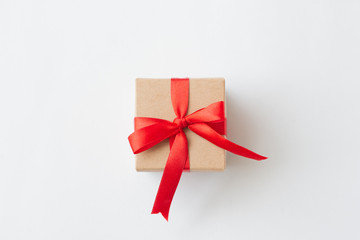 Brown paper gift box with red ribbon on white background.