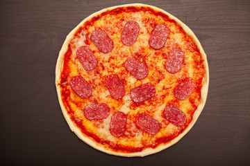 Tasty pizza with various flavored ingredients on a dark background