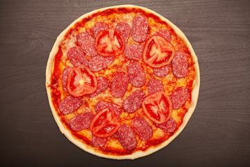 Tasty pizza with various flavored ingredients on a dark background