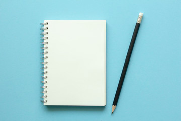 notebook and pencil on blue background