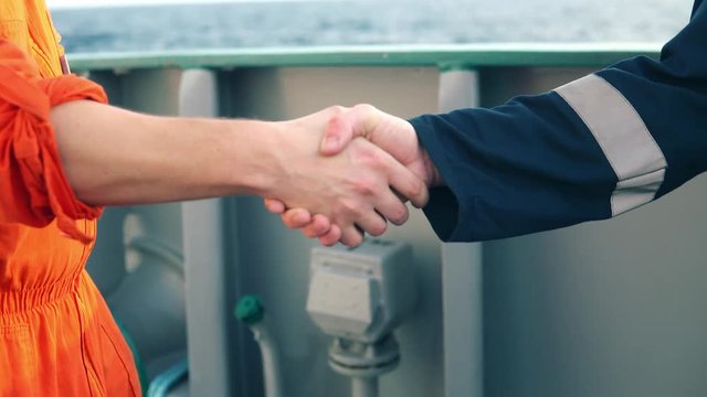 marine contractor businessman handshaking with worker on the ship. Handshake of two boilersuits with different color. Business shipping background