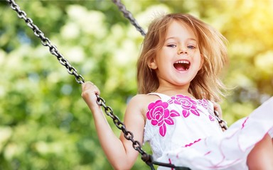 Little child blond girl having fun on a swing